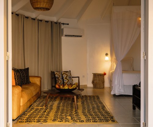 Área de estar com sofá e arte africana no bangalô de praia no Bom Bom Beach Resort