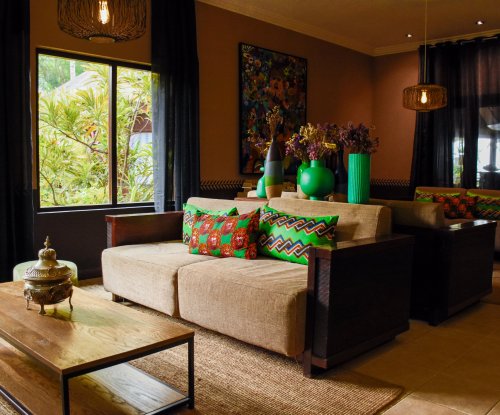 Cozy lobby area at Omali with colorful pillows, decorative vases, and plants by the window