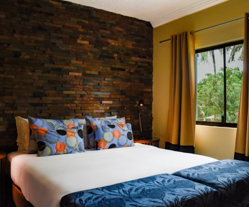 Bedroom with blue ottomans, stone wall, and a woven light fixture at Omali.