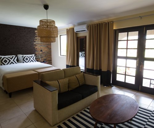 Suite at Omali with bed, couch, striped rug, and wooden accent wall.