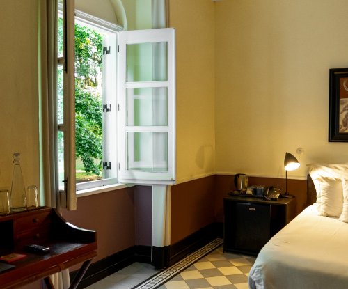 Quarto na Roça Sundy com uma janela aberta, uma cama e uma secretária