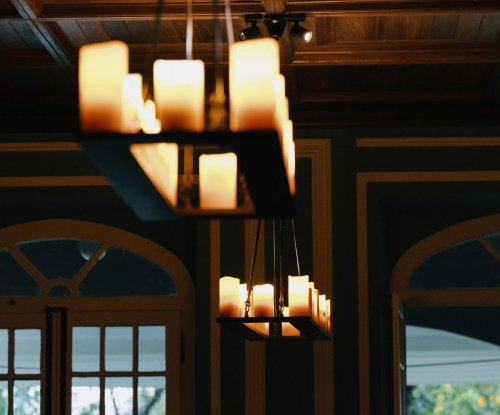 Lustre suspenso com velas, teto de madeira e janela ao fundo na Roça Sundy