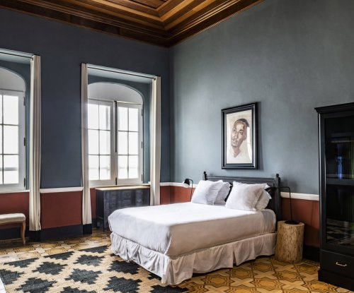 Quarto espaçoso com grandes janelas e design vintage no Roça Sundy Boutique Hotel.