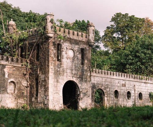 Ruínas de um antigo edifício de pedra rodeado por vegetação exuberante