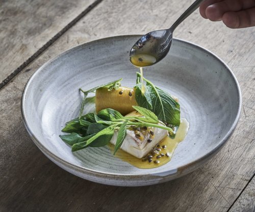 Prato de alta gastronomia apresentado numa mesa no restaurante OKA Sundy