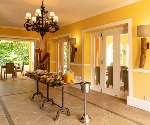 Breakfast buffet in the yellow dining room at Belo Monte, chandelier lighting and doors opening to the gardens.