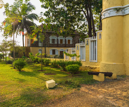 Main house of Belo Monte framed by trees, stone and yellow facade with arched windows and garden walkway.
