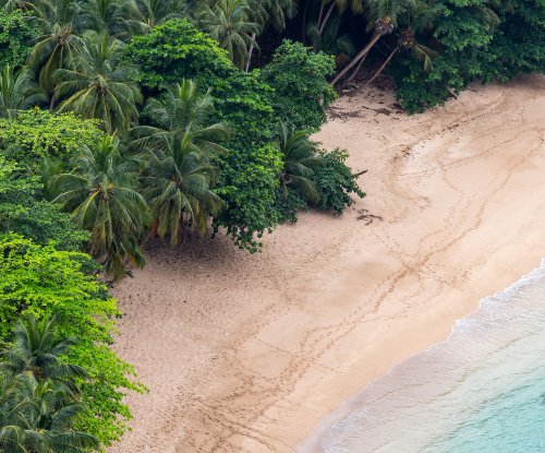 Vista aérea da Praia Banana perto do Hotel Belo Monte, dois hóspedes nas águas turquesa para um mergulho calmo