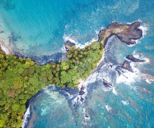 Vista aérea da Ilha do Príncipe com água cristalina de tom turquesa e vegetação exuberante da selva.