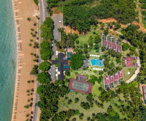 Vista aérea do hotel Omali com piscina, campo de ténis e jardins tropicais junto à praia, Ilha de São Tomé