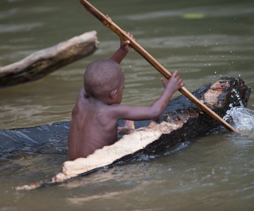 Child paddling a handmade wooden canoe in the river, Príncipe Island