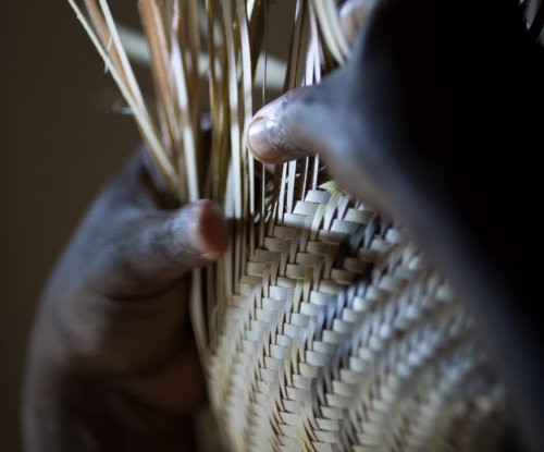 Pormenor das mãos de um artesão a tecer um cesto de palha, Ilha do Príncipe
