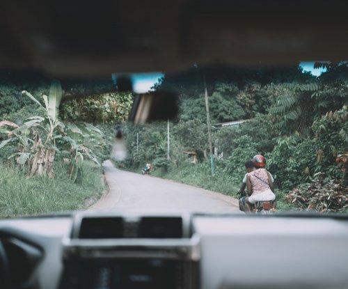 Estrada tropical vista do interior do carro com motociclista à frente, Ilha do Príncipe