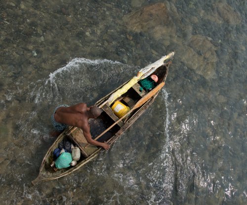 Vista de cima de um pescador numa canoa de madeira com redes e apetrechos de pesca, Ilha do Príncipe
