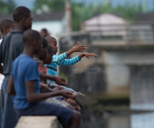 Crianças a pescar com linha do cais em Santo António, Ilha do Príncipe