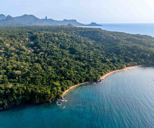 Vista aérea da costa de Sundy Praia com floresta tropical, praia e baía turquesa, Ilha do Príncipe