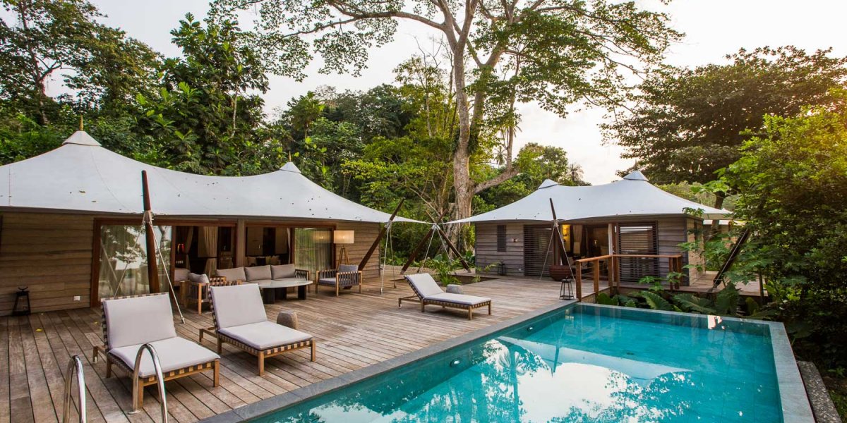 Pool with three loungers and in the background the three bedroom villa at Sundy Praia