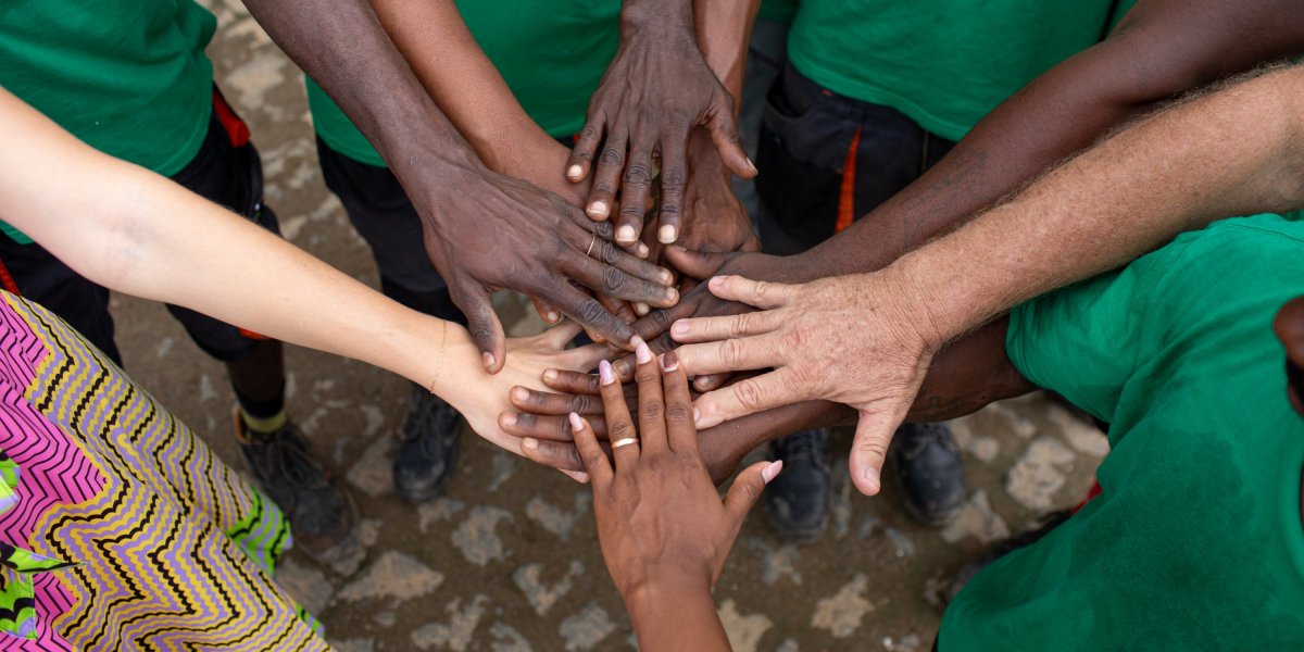 Circle of hands with different skin tones touching in the centre on Príncipe Island.