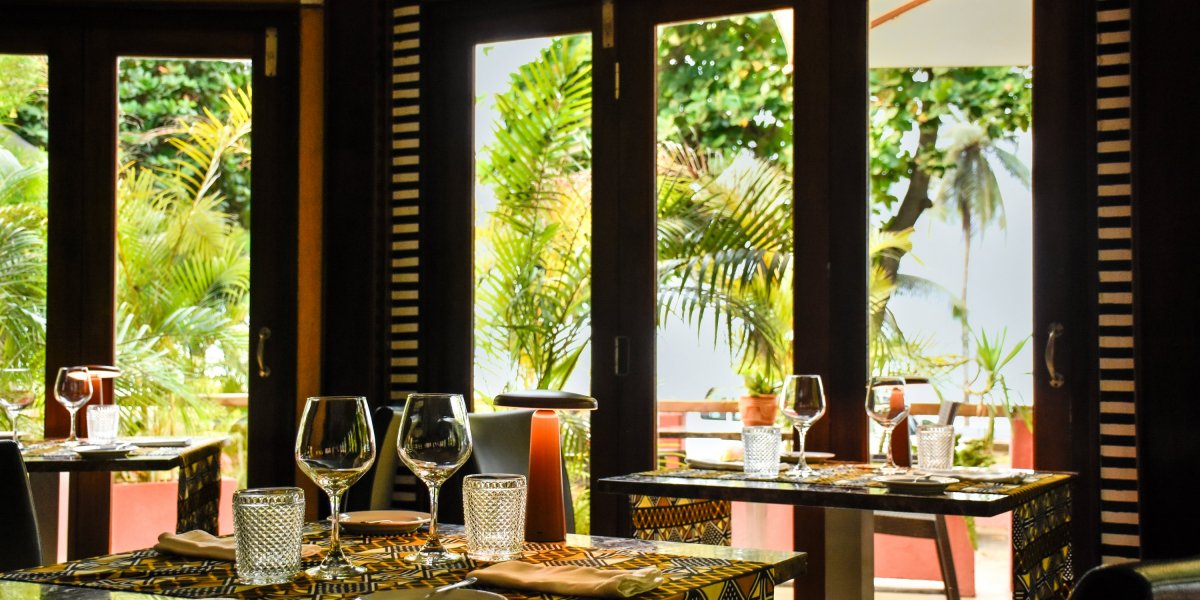 Área de refeições ao ar livre com mesas, cadeiras e guarda-sóis no Omali Restaurant, São Tomé