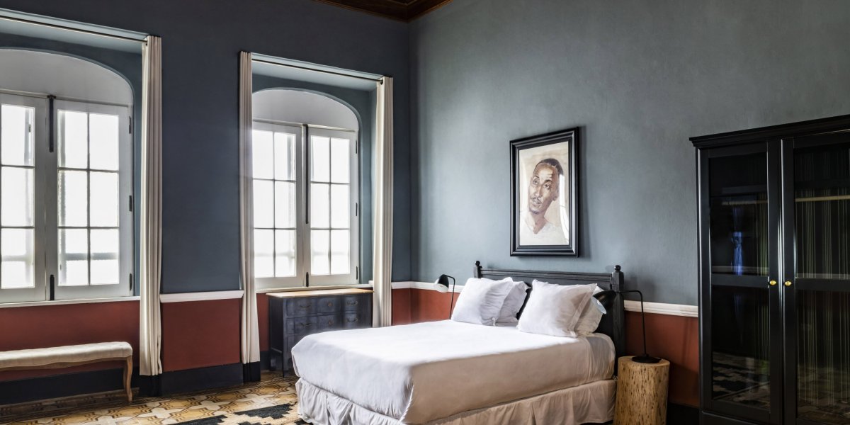 Spacious bedroom with large windows and vintage design at Roça Sundy Boutique Hotel.