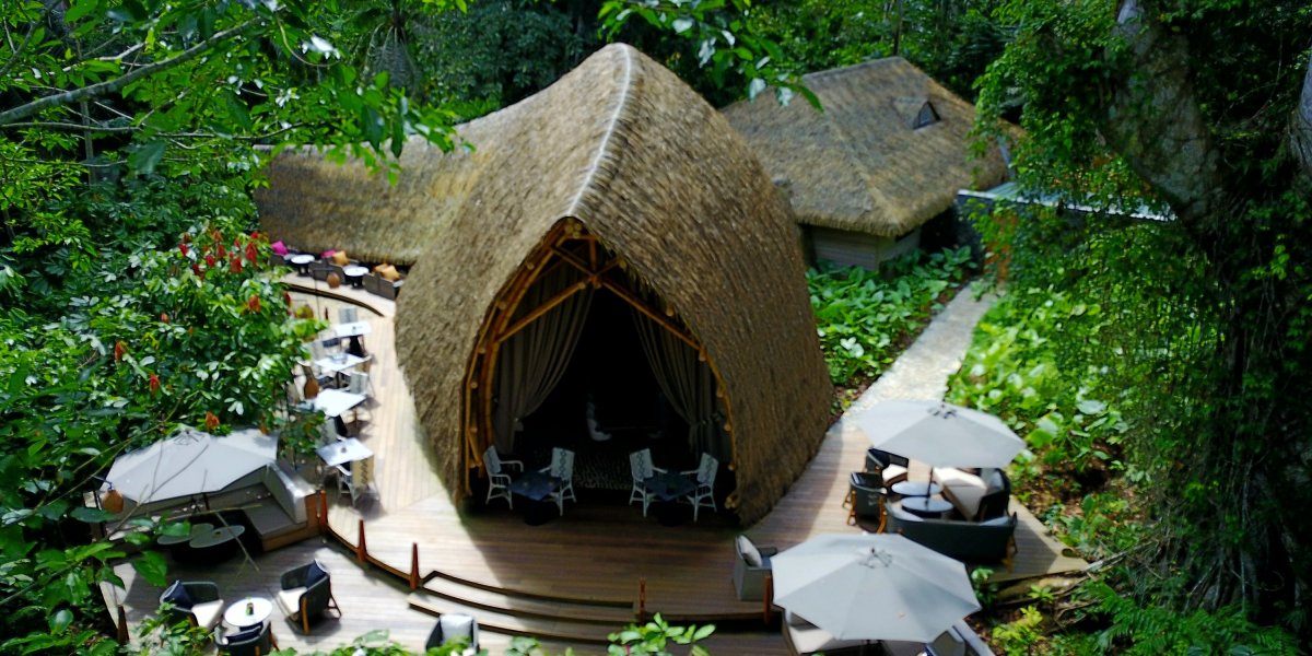 Top view of OKA Sundy Restaurant deck in the forest at Sundy Praia, shaded seating for open-air dining