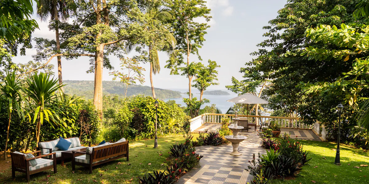 Terraço ajardinado do Belo Monte com caminho em mosaico, fonte e zona de estar, com vista para a baía na Ilha do Príncipe.
