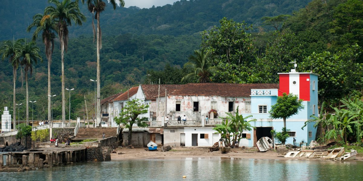 Porto de Santo António com edifícios coloniais e farol vermelho e branco, Ilha do Príncipe