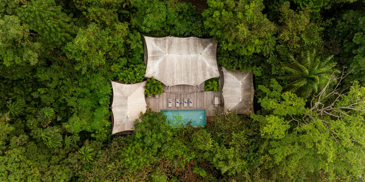 Aerial view of the Sundy Praia Pool Villa with private pool and wooden deck, nestled within the tropical rainforest, Príncipe Island