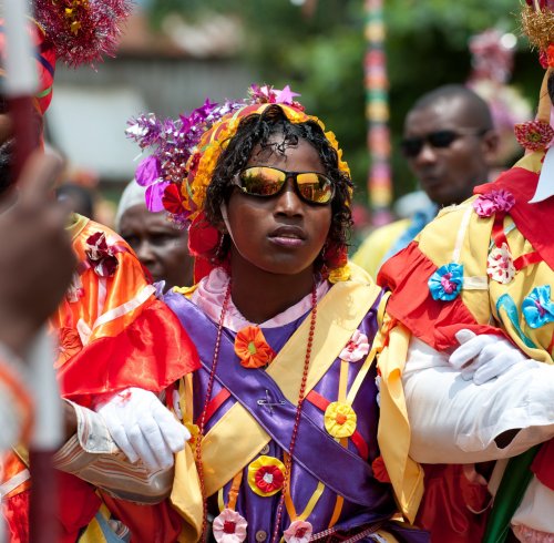 Performers in ribboned costumes and beaded crowns during the Auto de Floripes parade in Santo António
