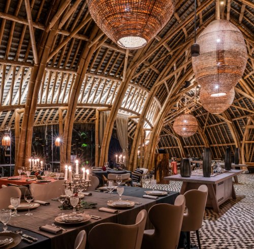 Interior view of OKA Sundy restaurant featuring bamboo architecture, decorative lighting, and dining tables