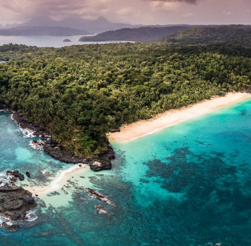 Aerial view of Príncipe Island, with crystal-clear water and dense rainforest vegetation.