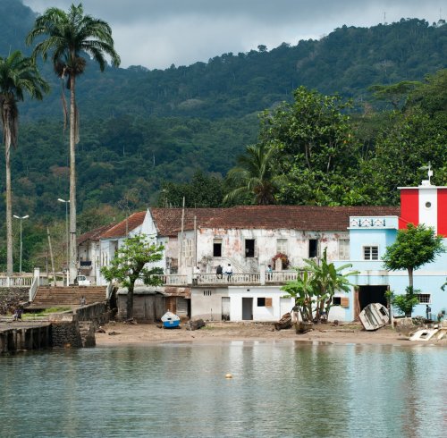 Porto de Santo António com edifícios coloniais e farol vermelho e branco, Ilha do Príncipe