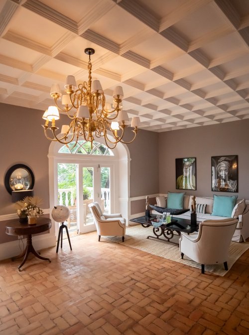 Belo Monte lounge with a coffered ceiling, gold chandelier and terracotta brick floor opening onto the terrace