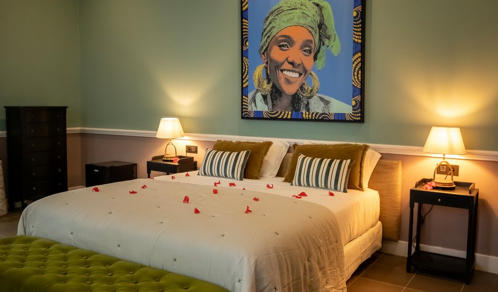 Quarto Duplo Vista Jardim do Belo Monte com cama de casal, banco verde e retrato emoldurado
