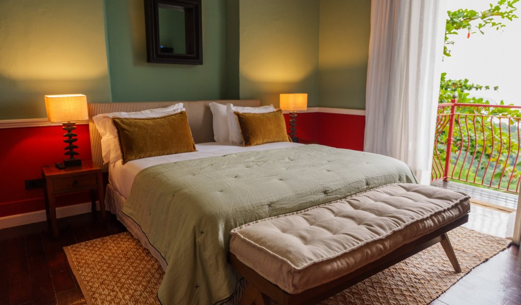 Suite Panorâmica do Belo Monte com cama de casal, colcha verde e varanda sobre a floresta tropical