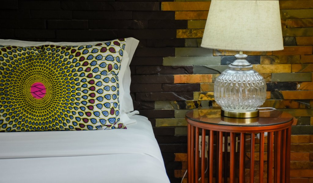 Bed with a patterned cushion and a vintage lamp at Omali