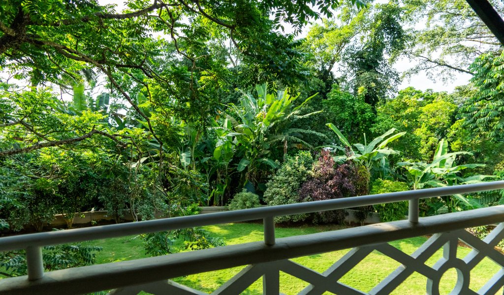 View from a bedroom at Roça Sundy showing a balcony with lush greenery