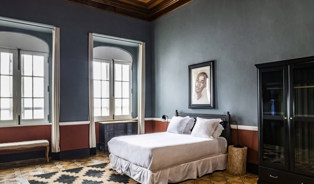 Spacious bedroom with large windows and vintage design at Roça Sundy Boutique Hotel.