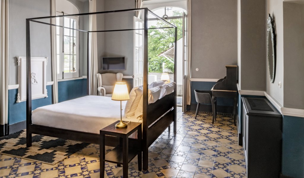 Spacious suite at Eclipse House in Roça Sundy with a four-poster bed, desk, and wooden ceiling