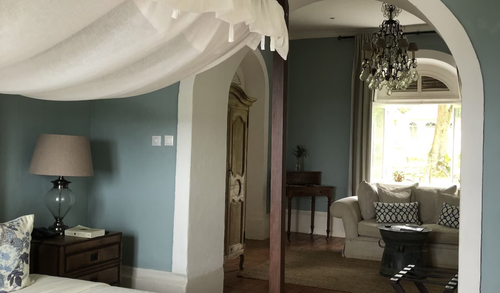 Panoramic Suite interior at Belo Monte, canopy bed and arched doorway leading to a separate lounge with chandelier.