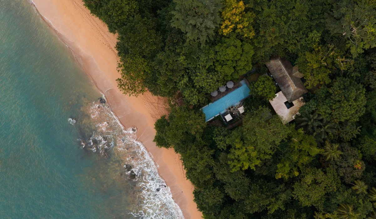 Aerial view of the Sundy Praia pool villa nestled in the rainforest beside the beach, Príncipe Island