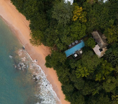 Aerial view of Sundy Praia beach with golden sand, turquoise sea and the pool villa nestled in the rainforest, Príncipe Island