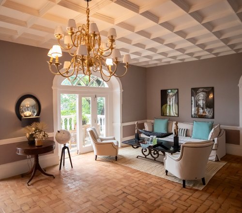 Belo Monte lounge with a coffered ceiling, gold chandelier and terracotta brick floor opening onto the terrace