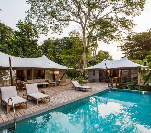 Piscina com três espreguiçadeiras e ao fundo a moradia de três quartos no Sundy Praia