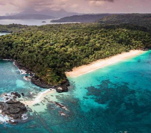 Aerial view of Príncipe Island, with crystal-clear water and dense rainforest vegetation.