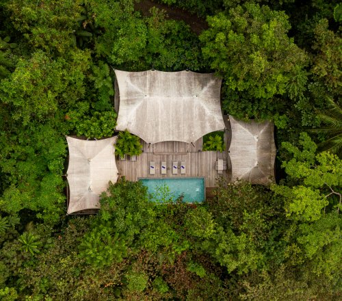 Vista aérea da Pool Villa de Sundy Praia com piscina privada e deck em madeira, integrada na floresta tropical, Ilha do Príncipe